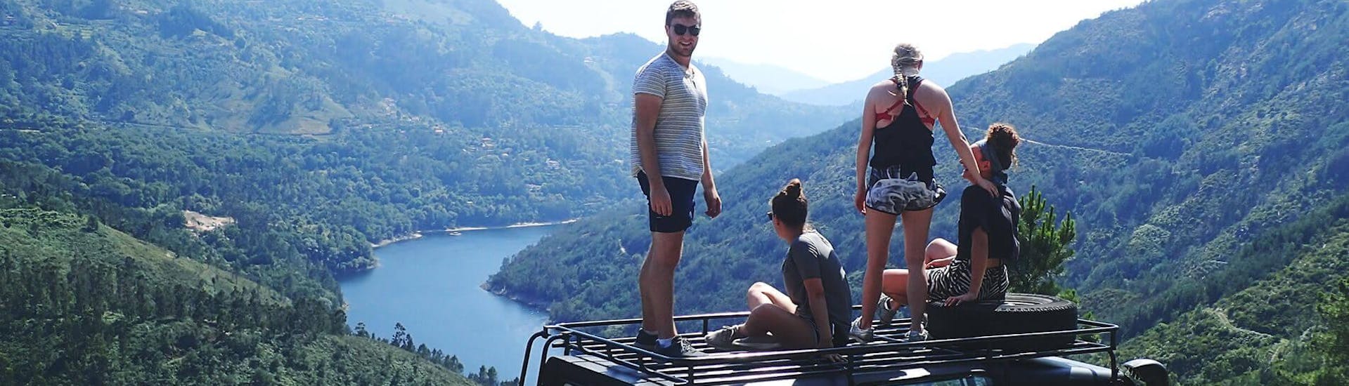 Eine Gruppe junger Leute steht auf dem Dach eines Geländewagens von Oporto Adventure Tours und genießt den Ausblick auf die atemberaubende Landschaft um sich herum.