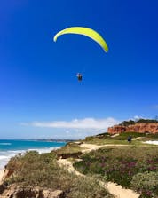 A view of a flight flying above the ocean and the beach where you can do paragliding in Albufeira. 