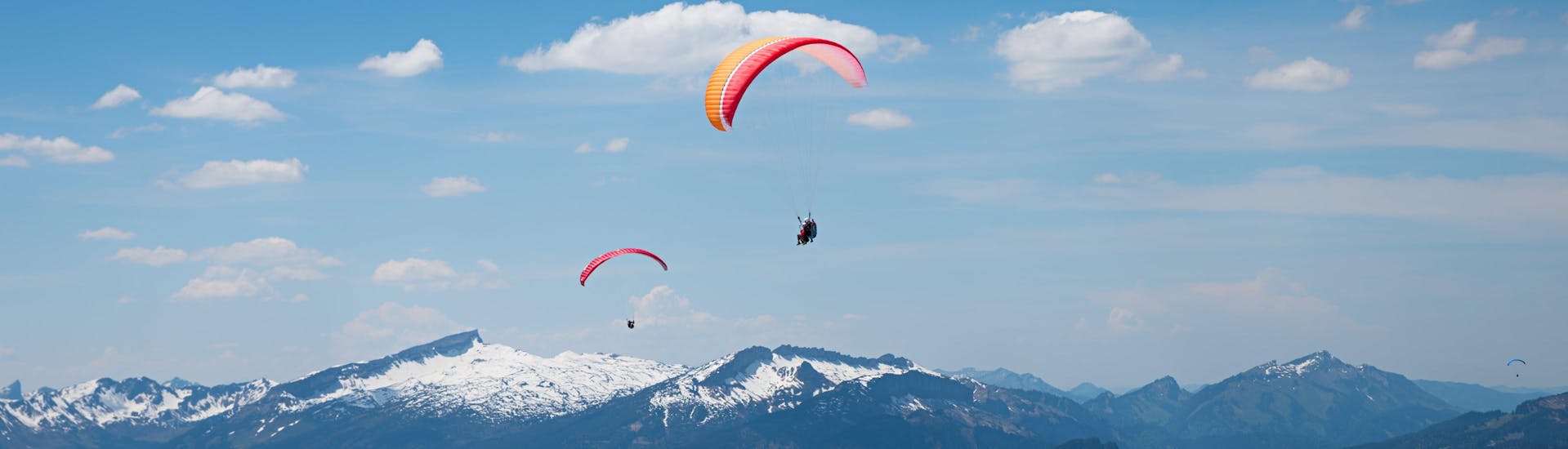 A tandem master and his passenger are sailing through cloudy skies while paragliding in Allgäu.