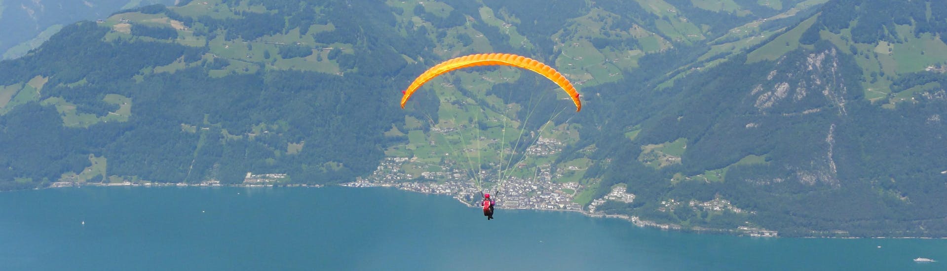 A tandem master and his passenger are sailing through cloudy skies while paragliding in Eigenthal-Luzern.
