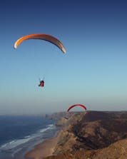 A view of a flight flying above the ocean and the cliffs where you can do paragliding in Lagos.