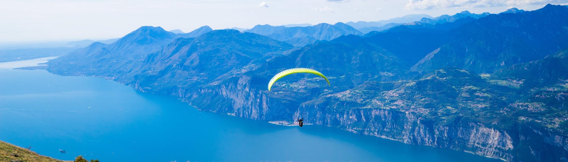 Ein einzelner Paraglider schwebt beim Paragliding am Gardasee über die malerische Landschaft.