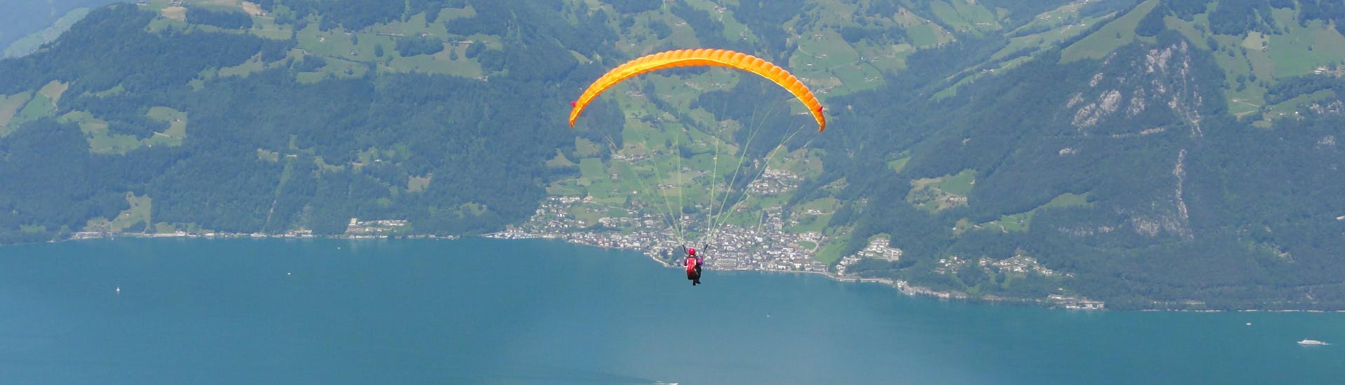 A tandem master and his passenger are sailing through cloudy skies while paragliding in Lucerne.