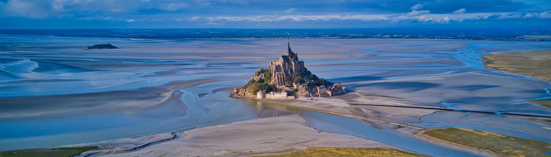 View of the Mont Saint Michel at low tide, one of the paragliding spots in Normandy, France.