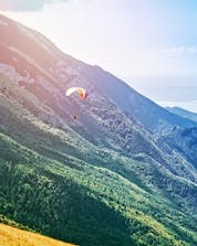 A paraglider can be seen flying towards Lake Garda while paragliding from Monte Baldo.