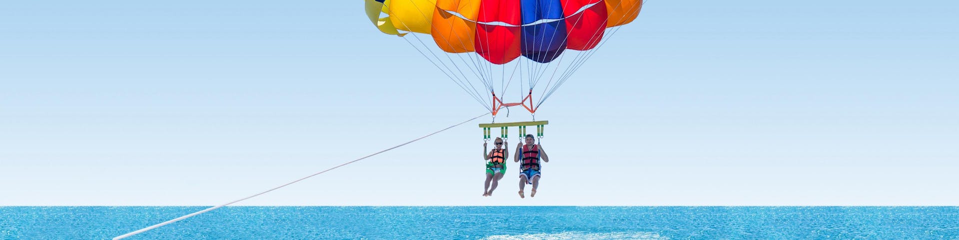 Friends are parasailing in the blue sky over the ocean
