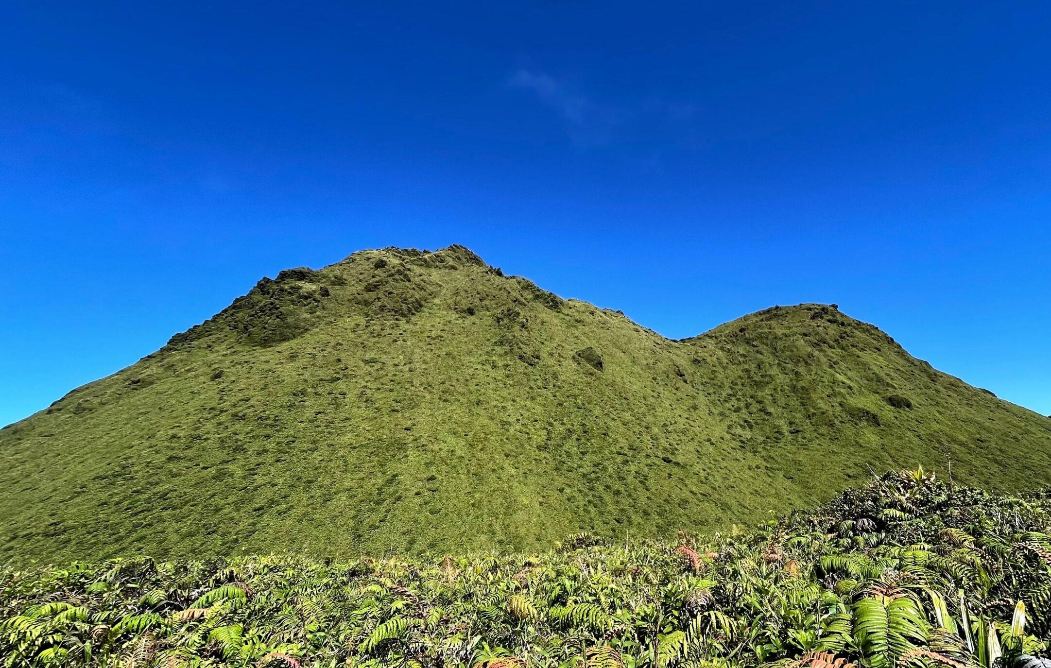 Ein üppiger Berg unter einem klaren blauen Himmel bei einer Wanderung mit Rando A2 Pas Martinique.