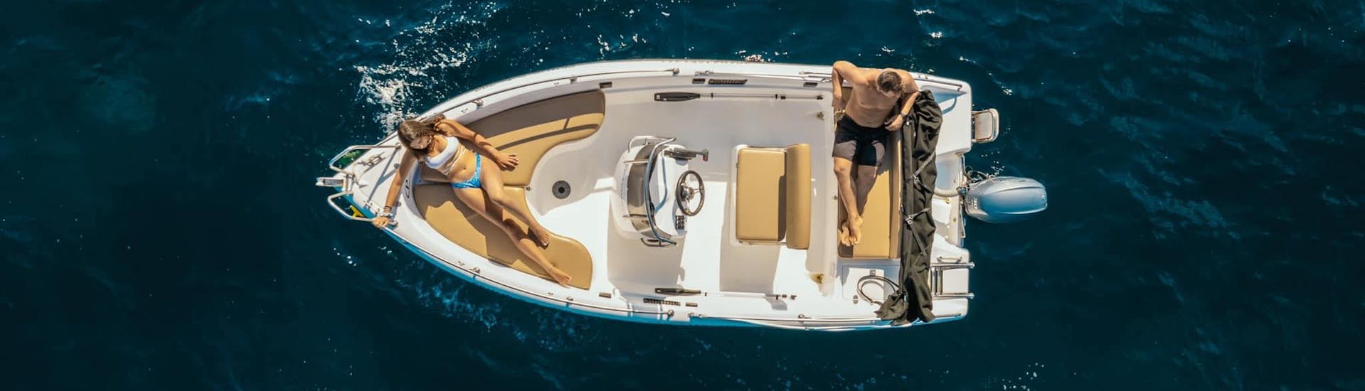 Two people are relaxing on one of the boats available for the rental with Poseidon Water Sports Ouranoupoli.