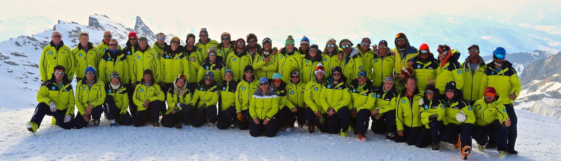 A group of skiers and their ski instructor from Prosneige Méribel are posing together in the snow while enjoying one of their ski lessons.