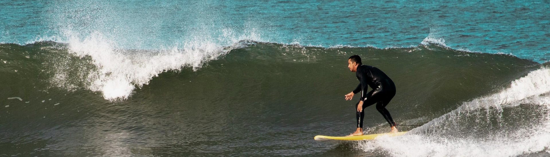 Una persona cavalca un'onda e si diverte durante una lezione di surf con Pura Vida Surfing School.