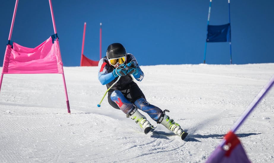 A skier is carving down a race slope during their Ski Lessons for Kids "Race Training" of All Levels with Ski School Snow Experts Pass Thurn.