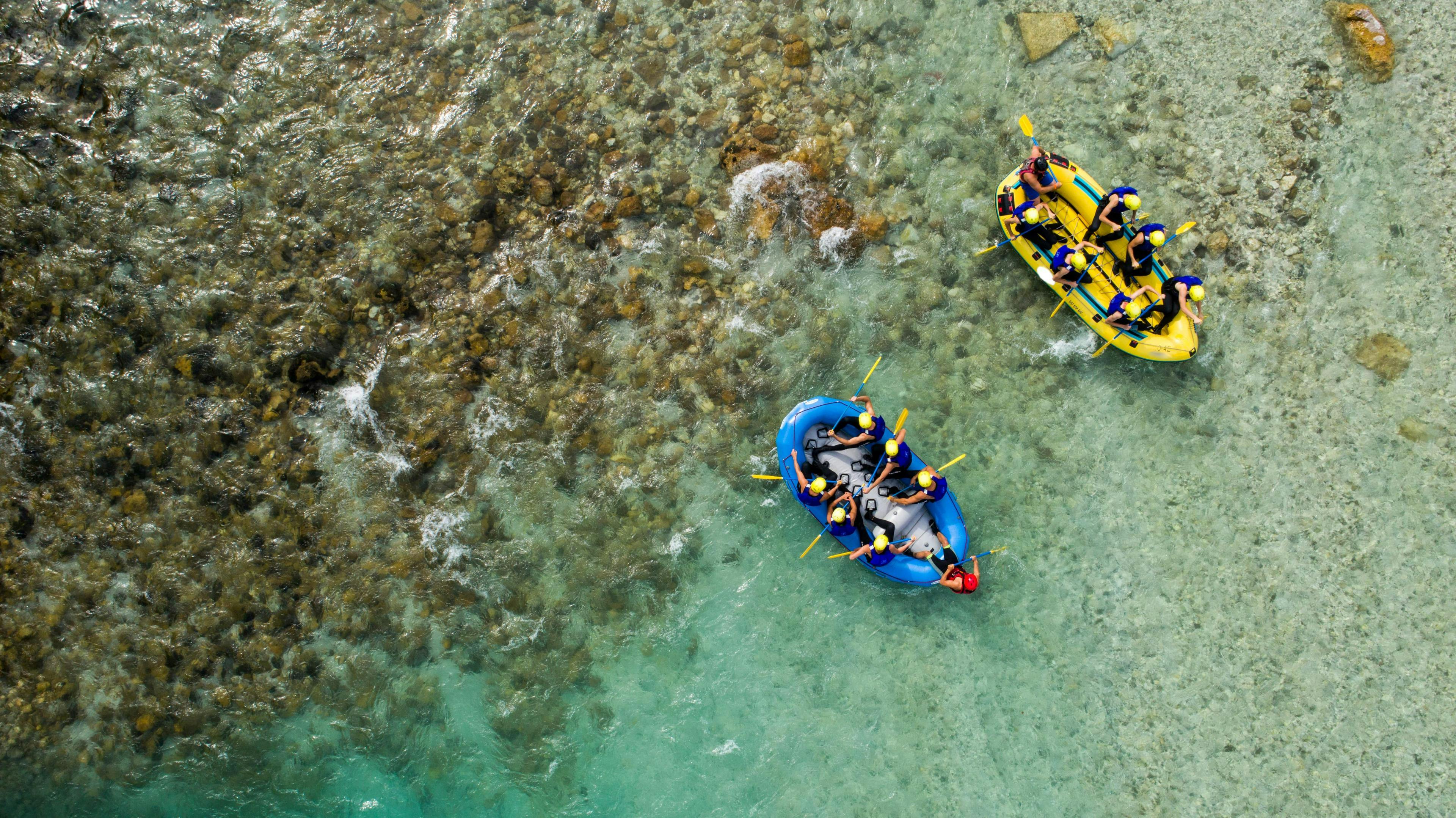 rafting-canyoning-bled_SEM-Resort-Hero Two groups of people are paddling across the Soca River while rafting near Bled.