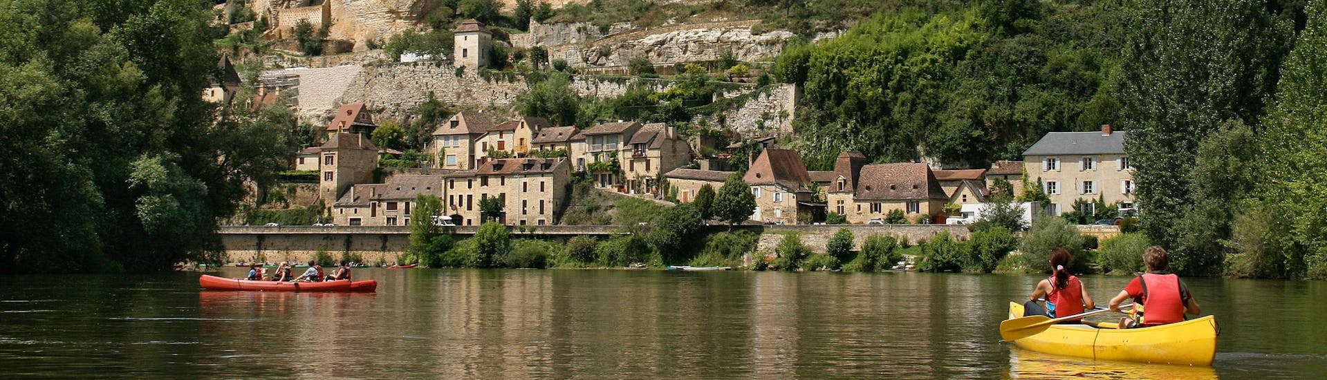 Des vacanciers profitent de leur vacances pour faire une sortie en canoë sur la Dordogne, et passent en dessous du château de Beynac.