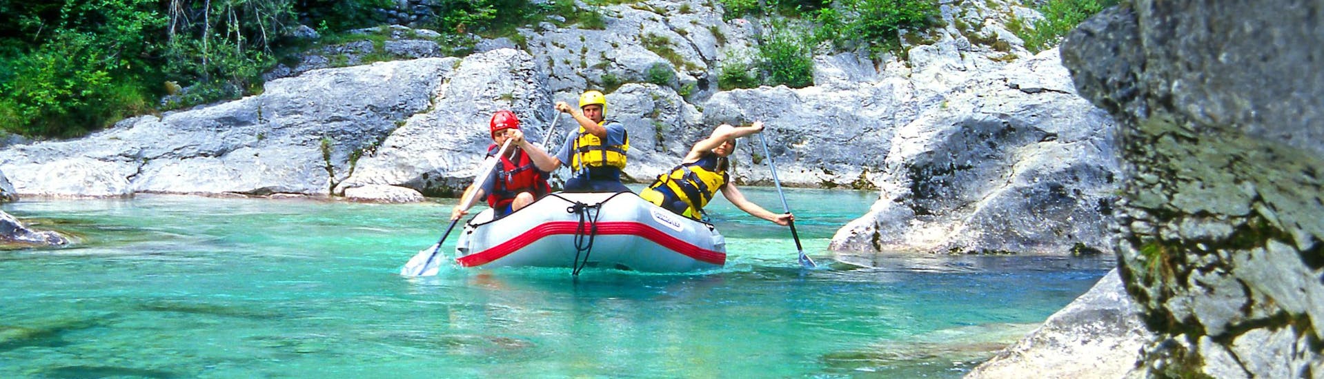 A group of young people enjoying some white water rafting fun in the rafting & canyoning hotspot of Soča Valley .