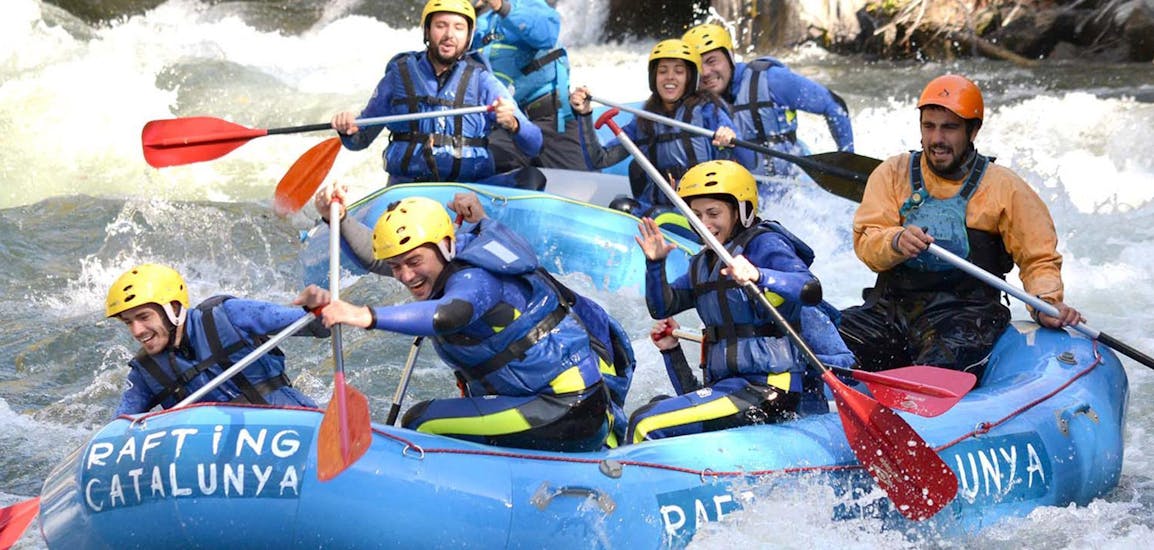 Un grupo de amigos se divierte mucho mientras reman por los rápidos salvajes con Rafting Catalunya.