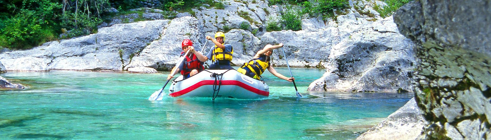 Un groupe d'amis pagaye dans un raft lors d'une activité de rafting dans la destination réputée pour le rafting Kobarid.