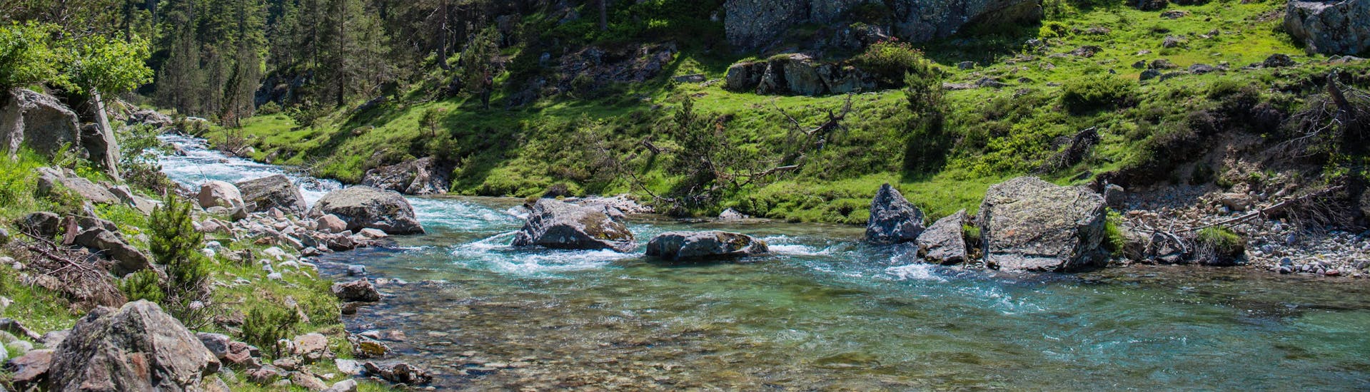 Une rivière coule au milieu d'un paysage verdoyant au milieu des Pyrénées, une destination prisées pour le rafting et le canyoning en France.