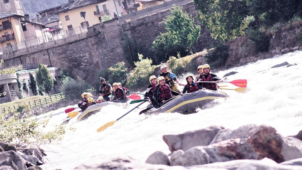 Una visuale sulla Dora Baltea, dove due gommoni di Rafting Republic stanno scendendo il fiume passando per uno dei vari centri storici del nord italia.
