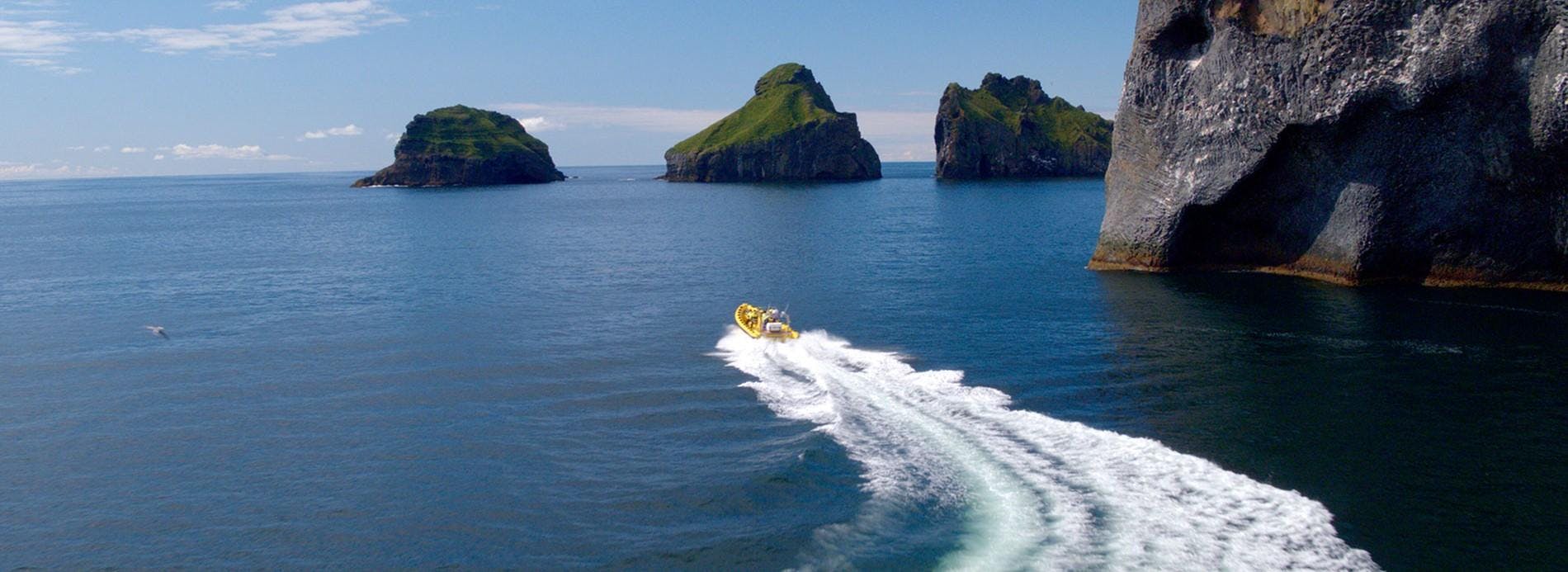 Ribsafari Vestmannaeyjar Een RIB-boot scheert over de IJslandse zee en snijdt door de golven.