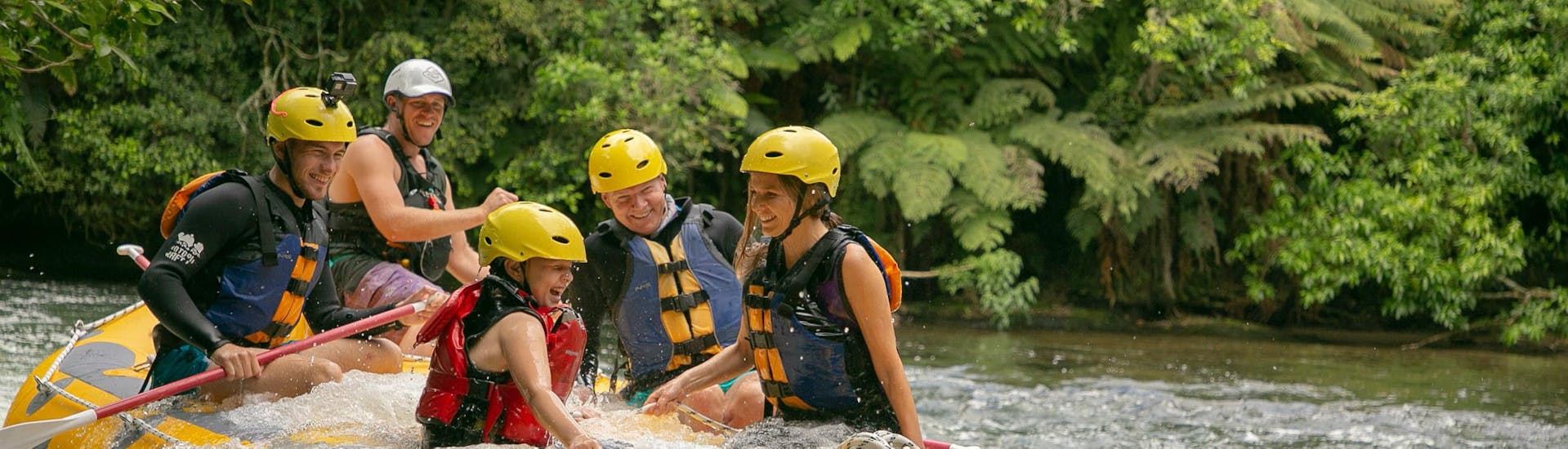 A family is laughing as water is splashing into their boat while rafting on Kaituna River with Rotorua Rafting in Okere falls.