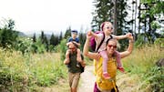 Una familia feliz con niños en la naturaleza pasándoselo en grande durante una actividad de senderismo.