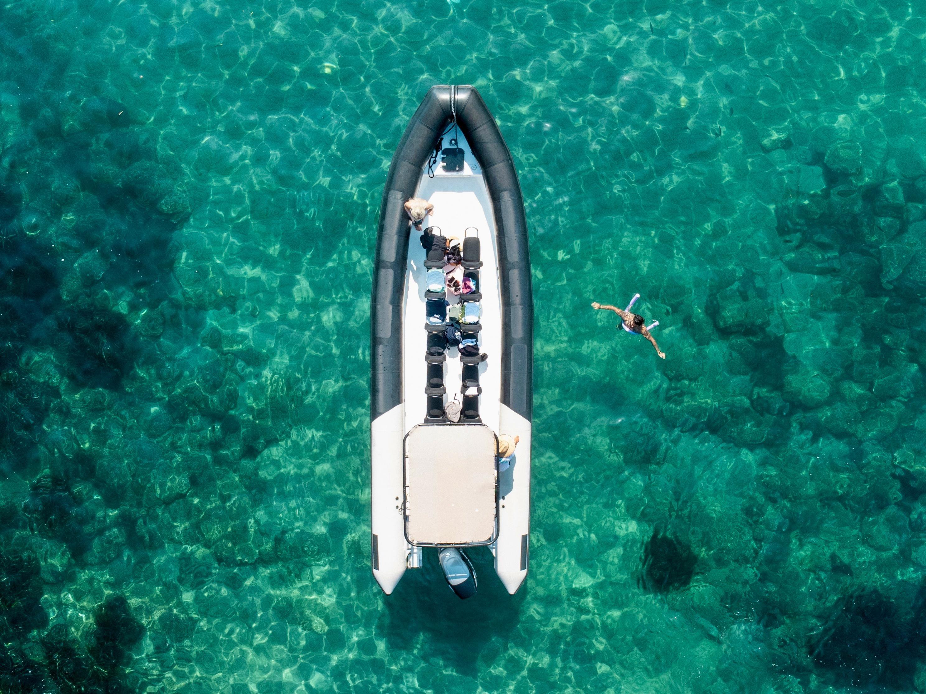 El barco TakSea Saint-Raphaël visto desde arriba sobre las aguas turquesas del Mediterráneo con gente nadando.