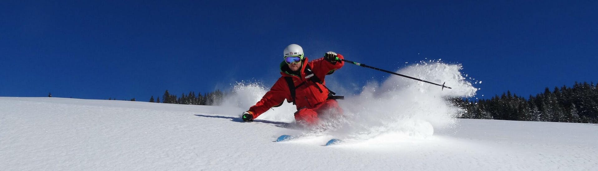 A ski instructor from the ski school S4 Snowsport Fieberbrunn is skiing through deep powder snow in the tyrolean ski resort of Fieberbrunn.