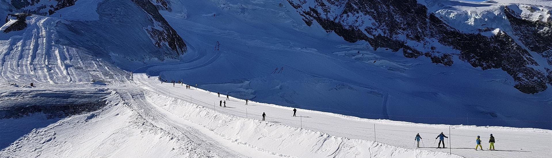 Adults and kids skiing in Saas Fee ski resort.