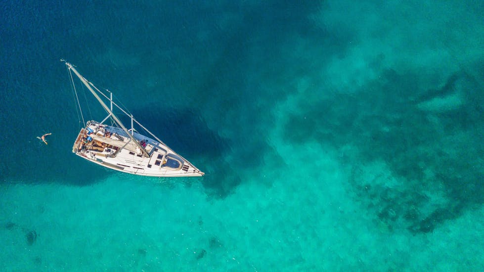 Sailboat from above in emerald water