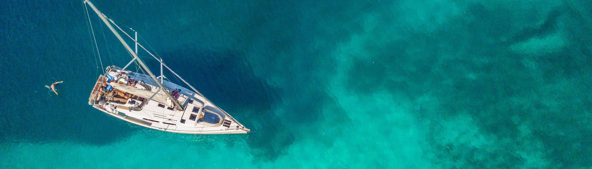 Sailboat from above in emerald water