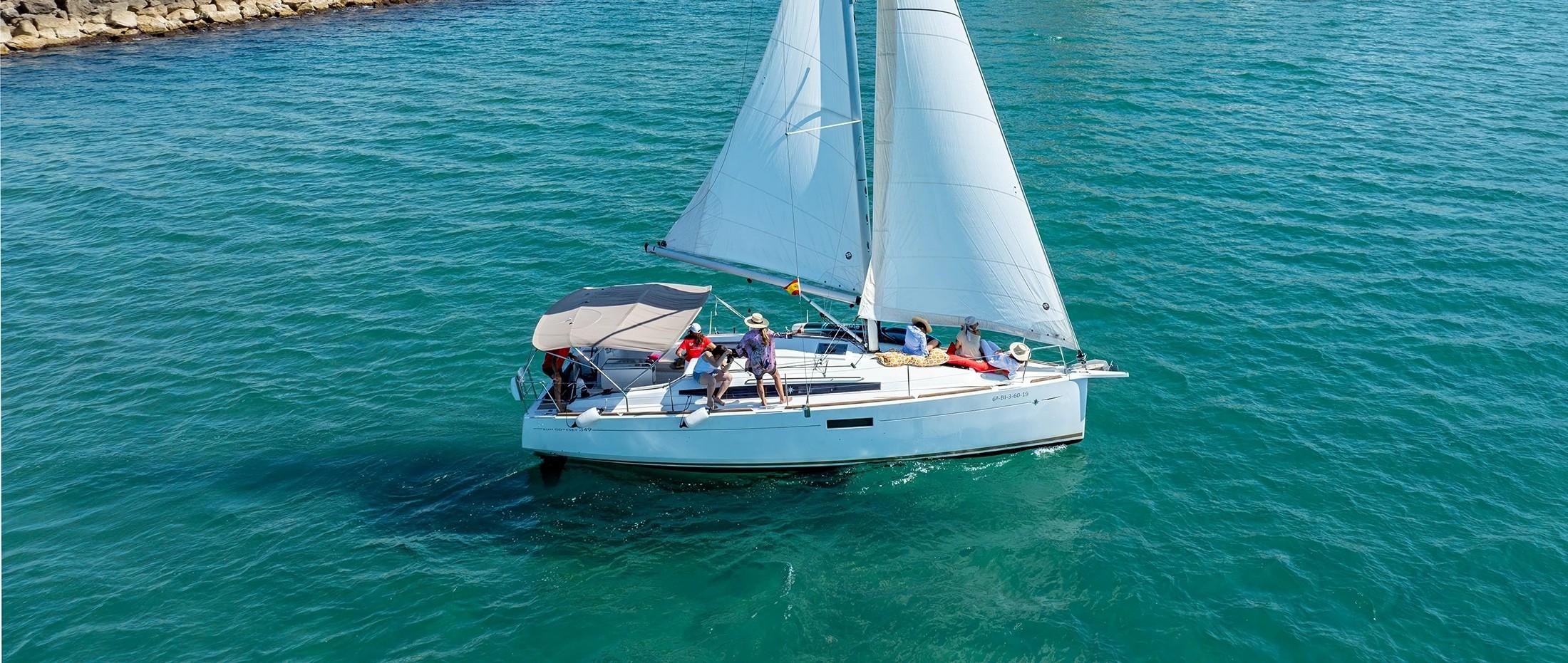 Een groep aan boord van de catamaran van Sailing Trip Sitges geniet en begeleidt het zeilen.