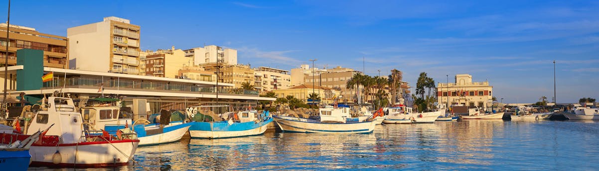 Santa Pola SEM Hero Mehrere Boote im Hafen von Santa Pola mit dem Dorf im Hintergrund.