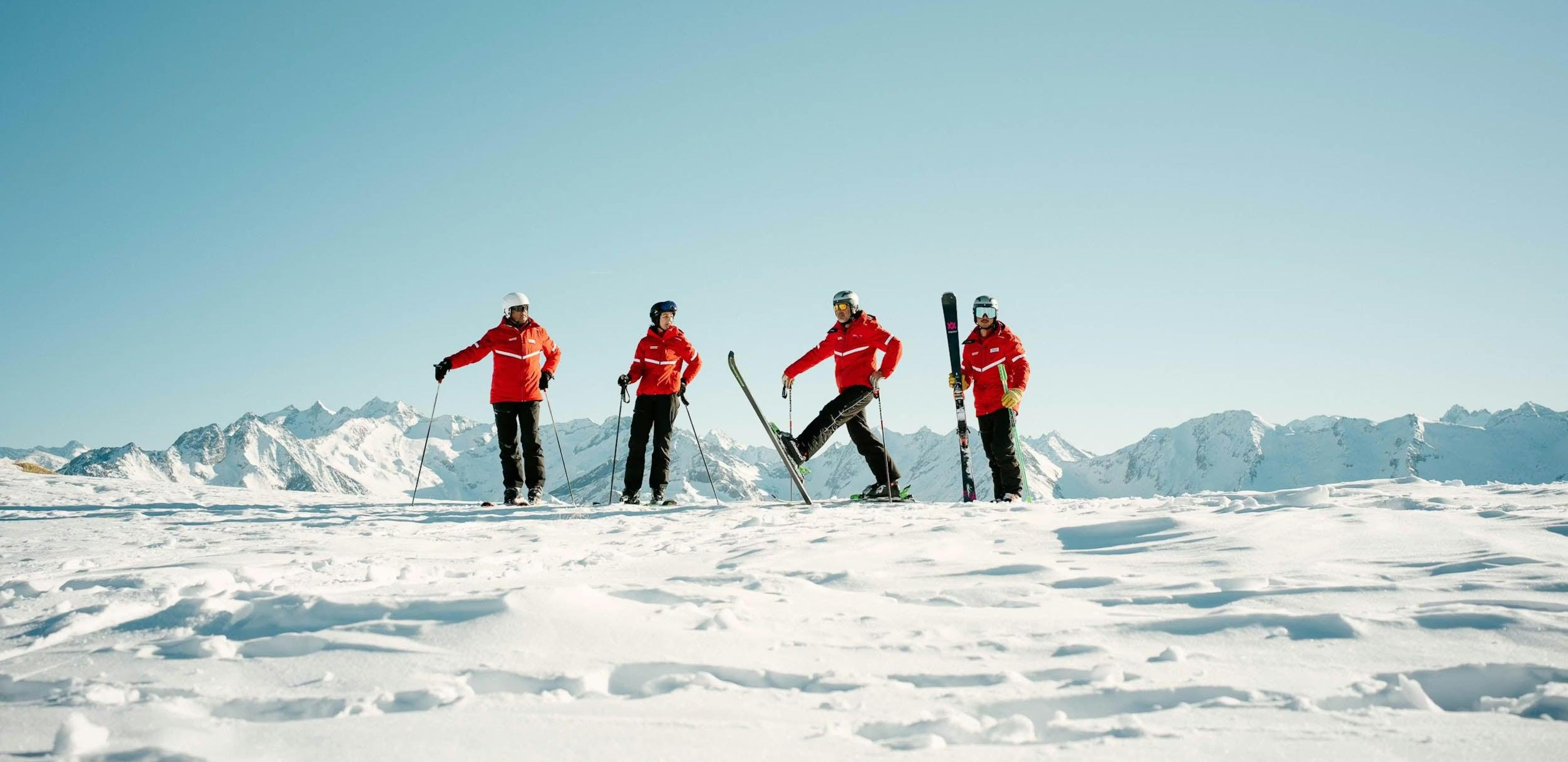 Vier skiërs met rode jassen op de top van een berg in Gerlos tijdens een skiles met Schischule Gerlos Total.