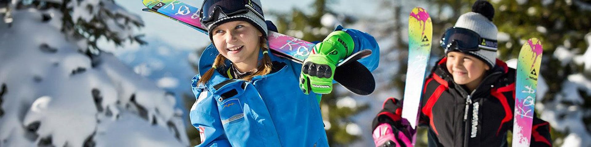Une jeune fille et un jeune garçon portent leurs skis en prévision de leur cours de ski avec l'école de ski Schneesportschule Black Forest Magic dans la station de ski de Feldberg.