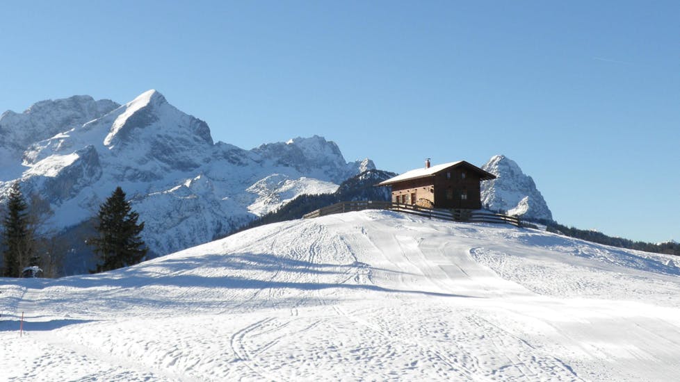Eine kleine Berghütte auf der Spitze eines Hügels im Skigebiet Garmisch-Classic, wo die Schneesportschule Morgenstern ihre Skikurse anbietet.