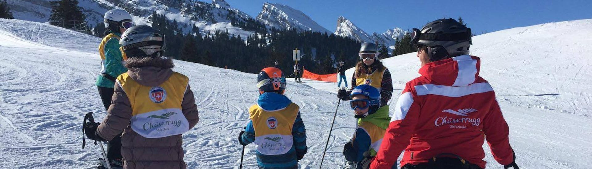 During the ski lessons with Swiss Ski School Chäserrugg, a ski instructor and her group of young skiers are admiring the beautiful mountains of the Chäserrugg ski resort.