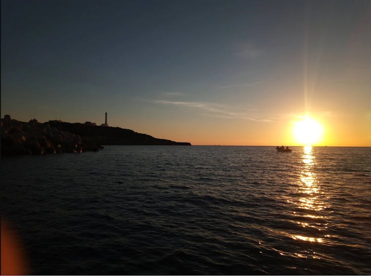 Picture of the view of the bay in front of the Leuca lighthouse at sunset from a boat from Leucos Escursioni Leuca.
