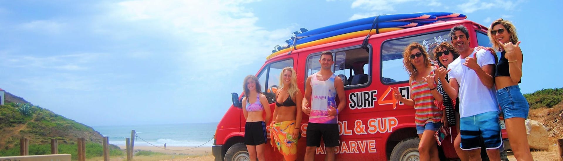 Un gruppo di persone sorride davanti al furgone di Surf4Fun Albufeira, una scuola di surf e sup di Albufeira.