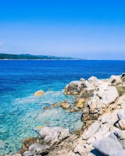 An image of the clear blue waters along the coastline of Sardinia that are frequently explored by visitors who go scuba diving near Porto Pollo.