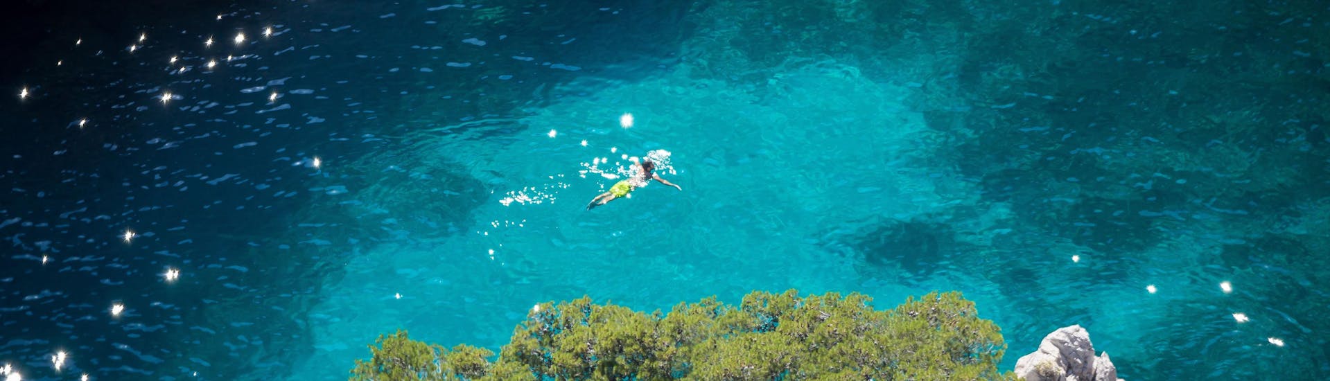 A swimmer is swimming in the turquoise waters of the Calanques National Park, one of the top diving and snorkeling spots on the French Riviera.