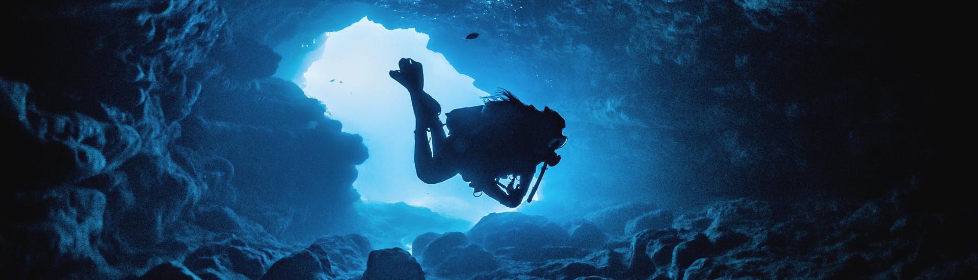 A scuba diver is exploring one of the many caves around the coastline of Malta, one of the famous scuba diving destinations in Europe.