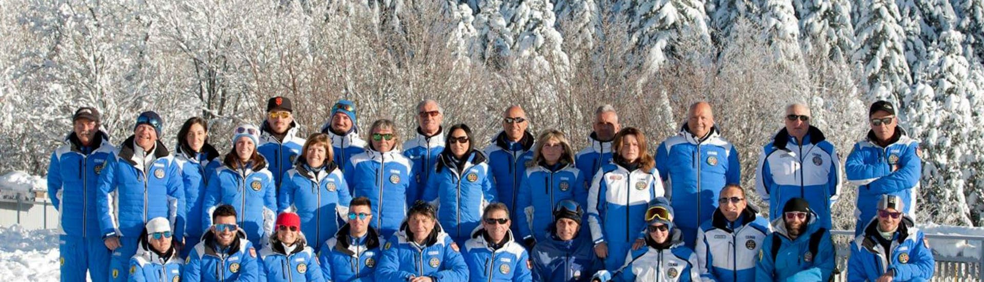 The ski instructors from the ski school Scuola di Sci Abetone are gathered in the snow with smiling faces that invite everyone to join their ski lessons.