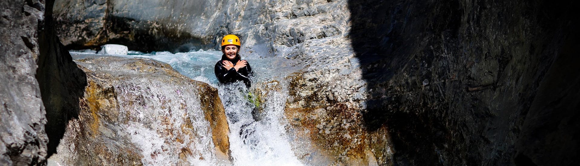 A woman is sliding down a natural slide during a canyoning tour with SerreChe Canyon.
