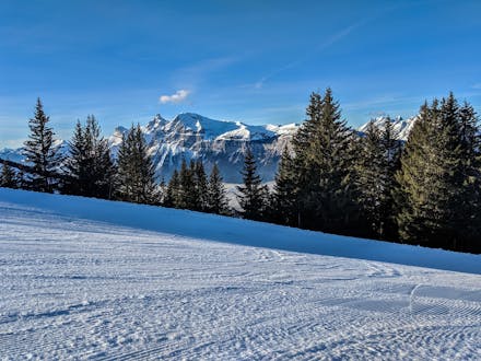 An image of a freshly prepared ski slope in the French ski resort of Les Carroz, a popular place to go skiing in the Grand Massif where visitors can book ski lessons with one of the local ski schools.