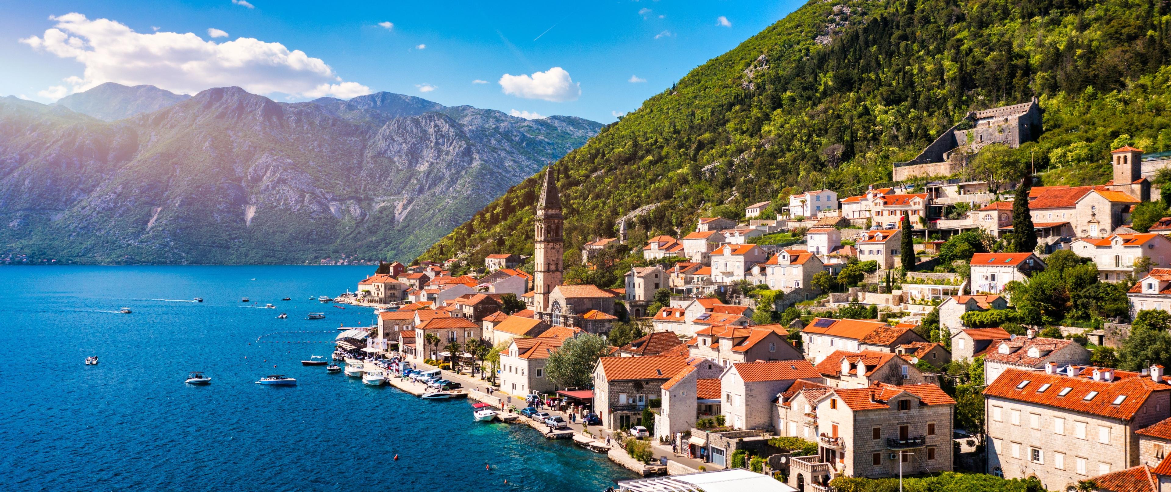 Vista de la costa de Perast con edificios históricos de piedra a lo largo de la bahía de Kotor.