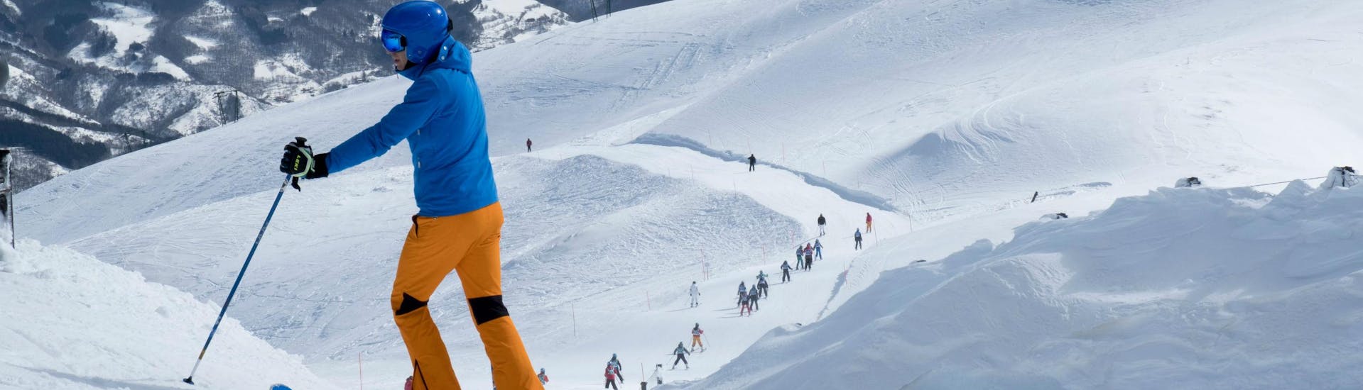 Uno sciatore ammira le piste del comprensorio sciistico di Abetone, dove le scuole di sci locali offrono una grande varietà di lezioni di sci per tutte le età e i livelli.