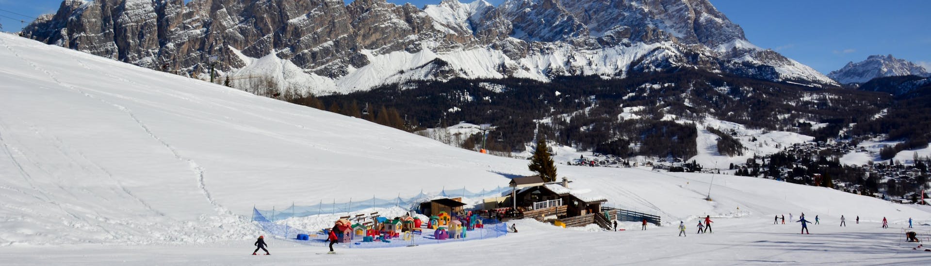 Una vista panoramica del paesaggio montano mentre le persone imparano a siare grazie alle lezioni di sci di una scuola di sci locale presso Val di Zoldo.