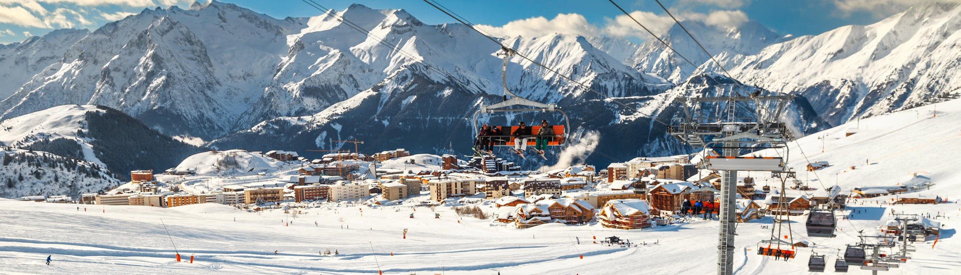 Ein Skifahrer legt bei seinem Skikurs eine Pause ein um den Ausblick auf das Skigebiet Alpe d'Huez von der Piste aus zu genießen.
