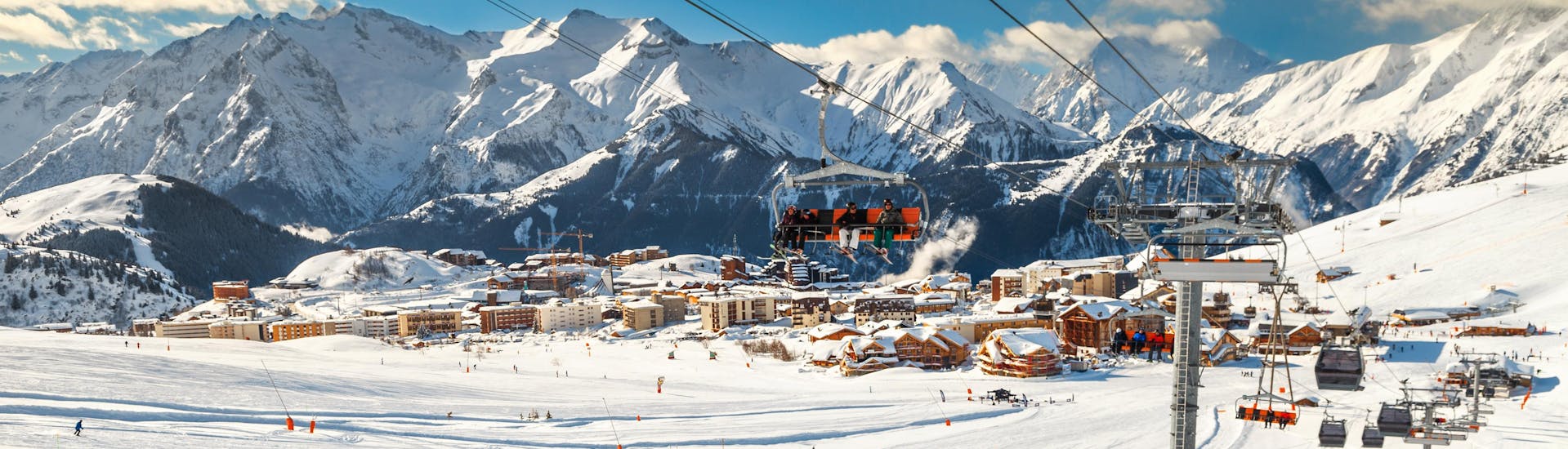 Un skieur fait une pause pendant son cours de ski pour profiter de la vue sur la station de l'Alpe d'Huez depuis les pistes.