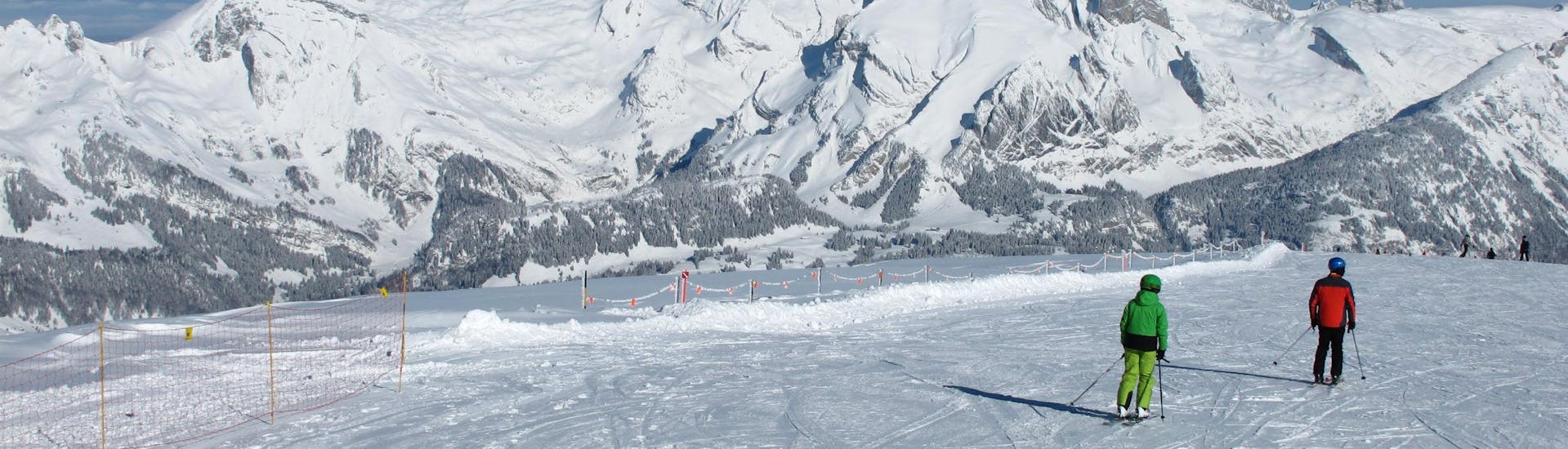 Two skiers are skiing down a freshly prepared ski slope in the ski resort of Alt St. Johann, where visitors can book ski lessons with the local ski schools.